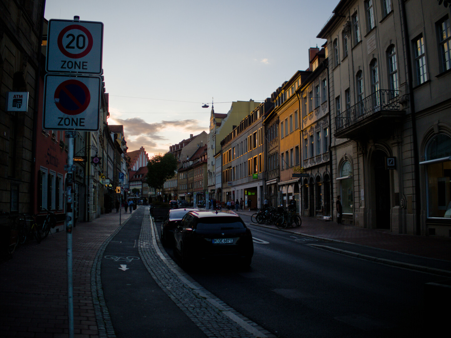 Straße Entlang Fotografiert. Links ein Schild. Alte Häuser Autos und Fahrräder. Goldene Stunde.
