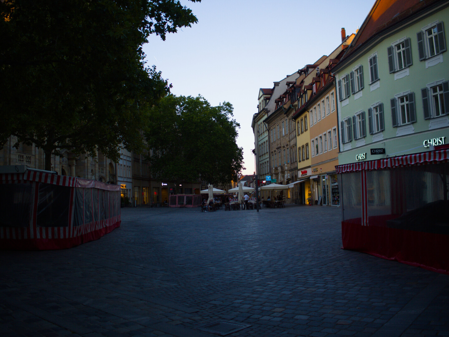 Fußgängerzone. Alte Gebäude. Straße entlang fotografiert. Pflastersteine. Marktstände.Bäume mit Blätter.