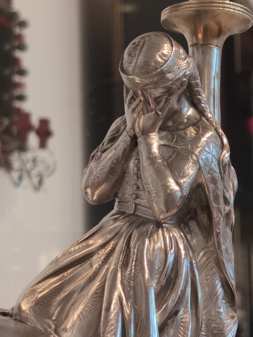 Detail of a silver cup showing a woman with hands over her face