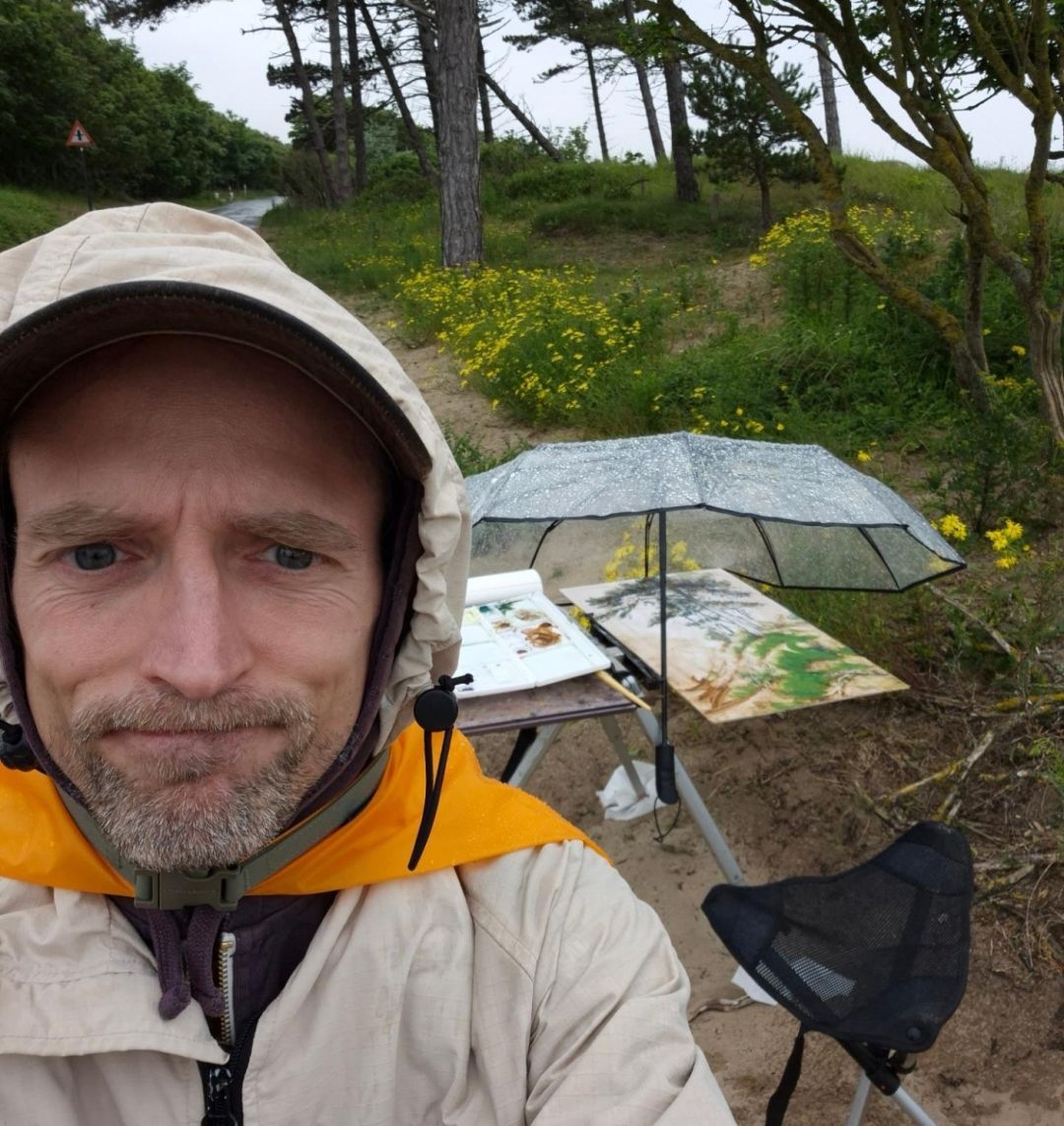 Thomas Schmall gets into despair in front of his easel, when it starts raining on his painting.