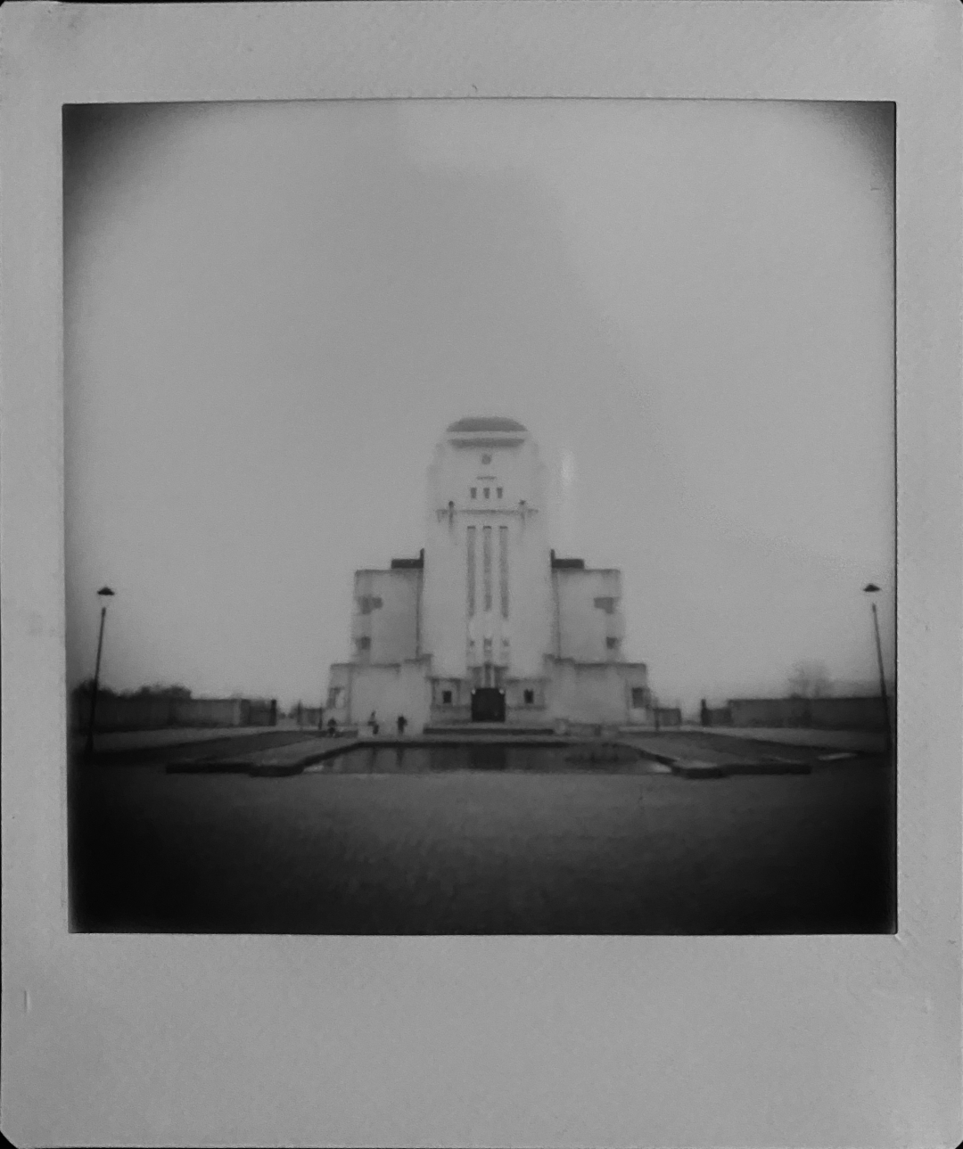 A black and white instant photo of a large blocky building. It’s got church vibes with a tower front and the building behind it, but is in fact a radio station from the early 1900s