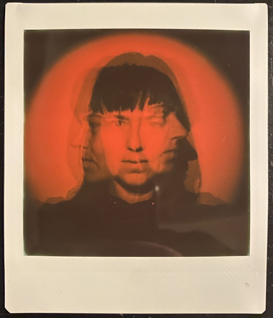 A black and red photo of myself, with one exposure looking straight in the camera, and another two looking towards each side, resulting in a blurred mix of the three positions.