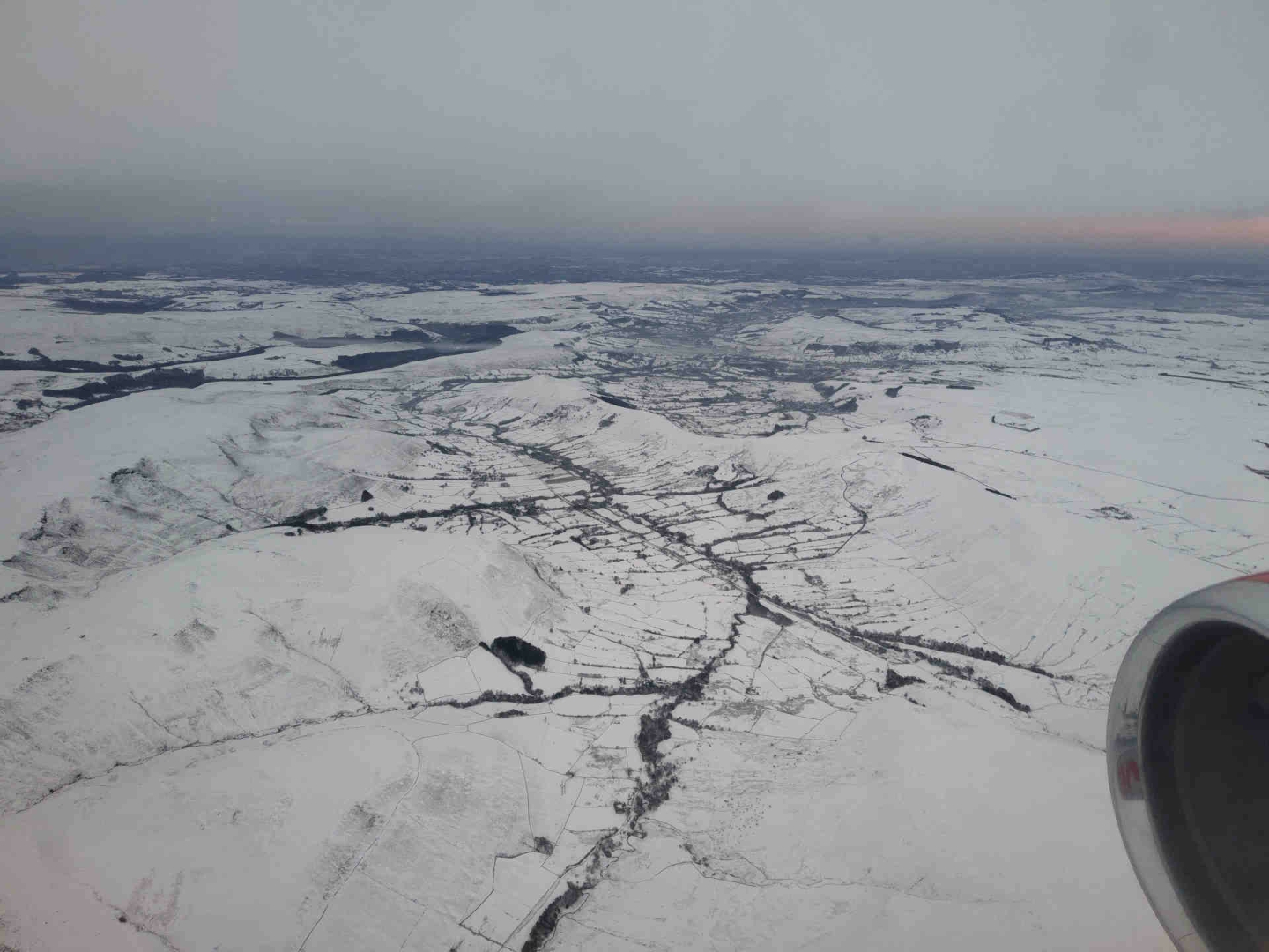 A snowy country landscape, with two large valleys - Edale and the Hope Valley - in the centre, divided by the Great Ridge, and moorland (Kinder Scout) to the left and hills & fields to the right