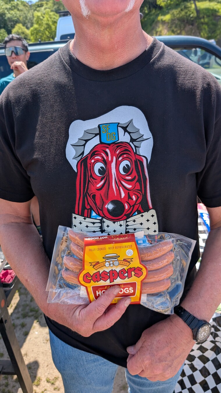 A man wearing a Doggie Dinner t-shirt and holding a package of Casper's hot dogs; San Francisco and Oakland historical food institutions