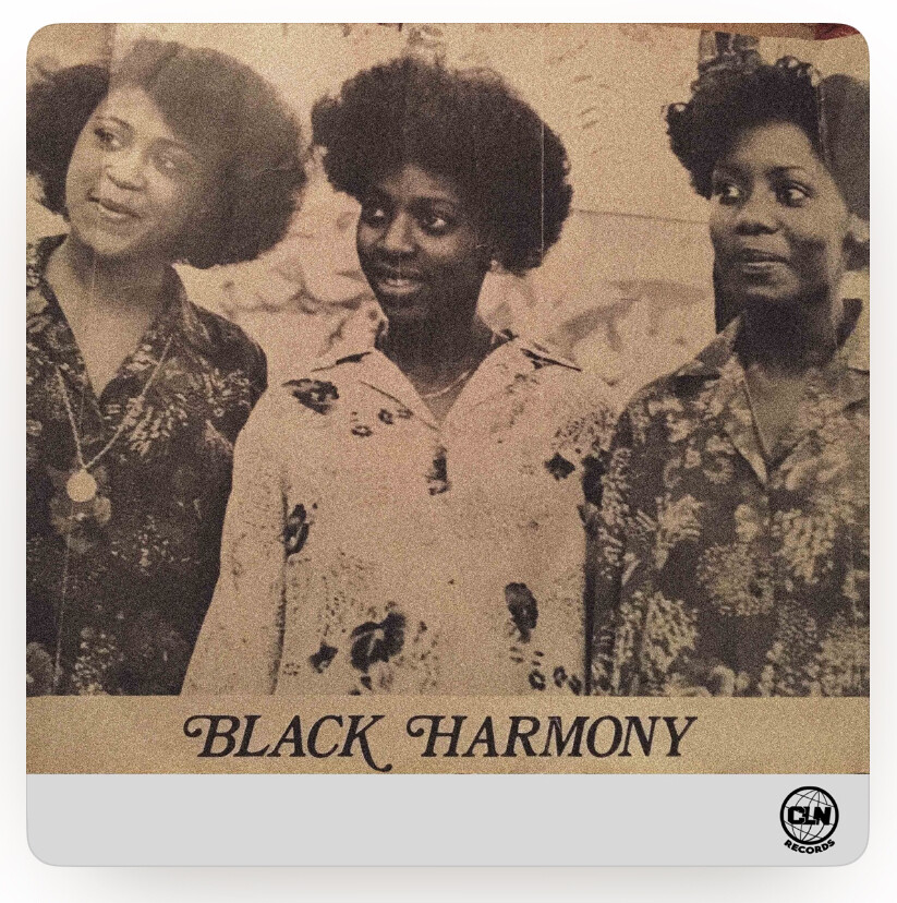 The vinyl album cover for “Let’s be Lovers” by Black Harmony. A black-and-white photo of three women with natural hairstyles, smiling and wearing floral-patterned shirts. The text 