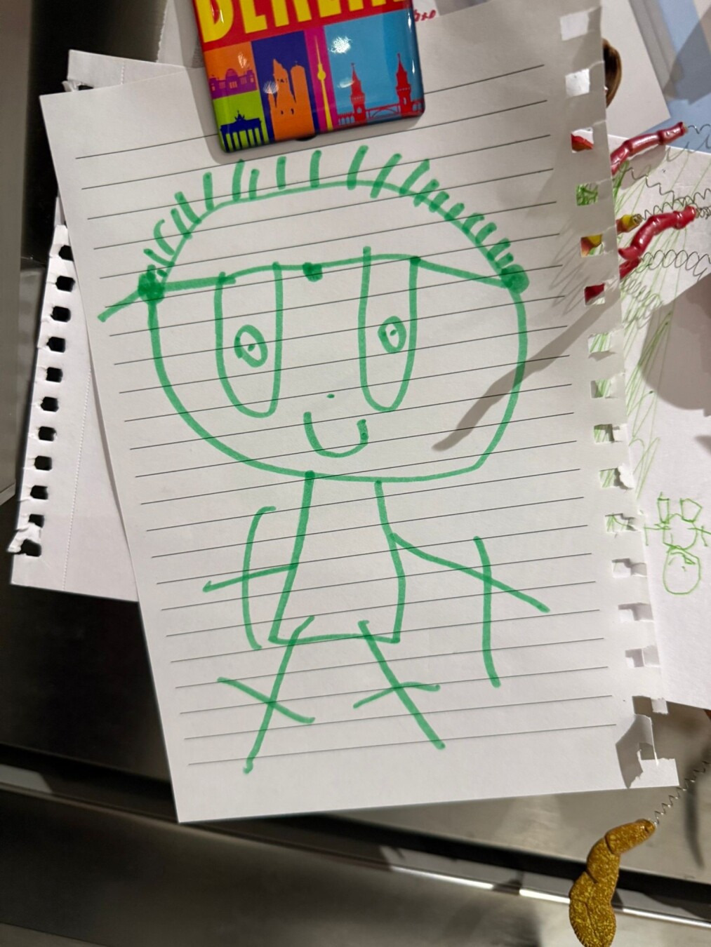 A picture of me in green felt pen on lined paper. Held on a refrigerator door but a magnet.