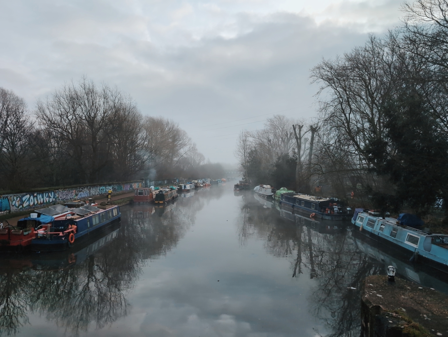 A misty canal lined with narrow boats