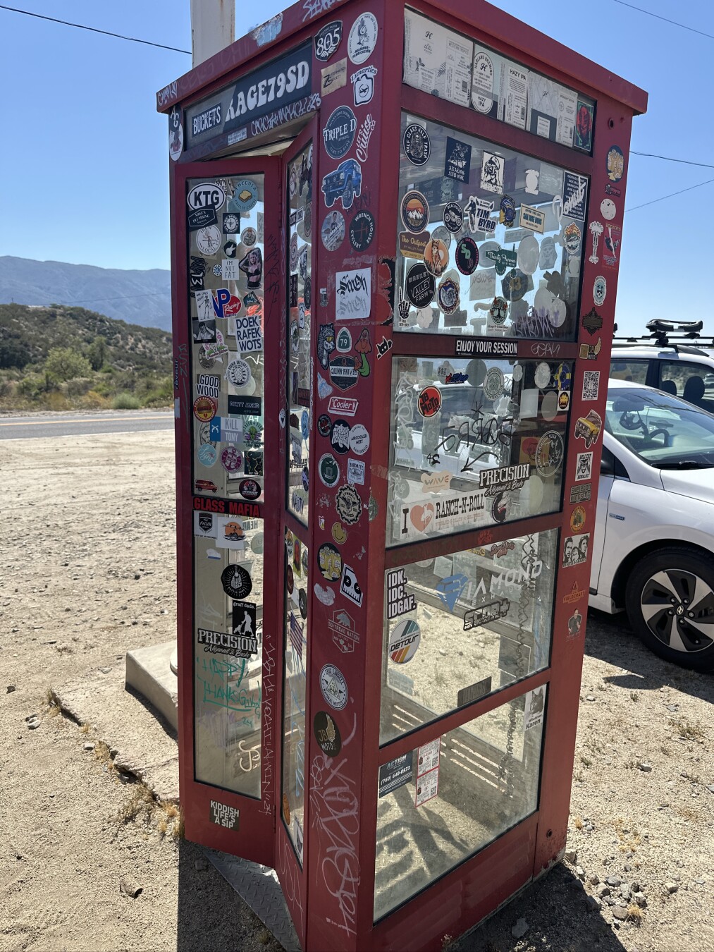 A red phone booth covered with stickers