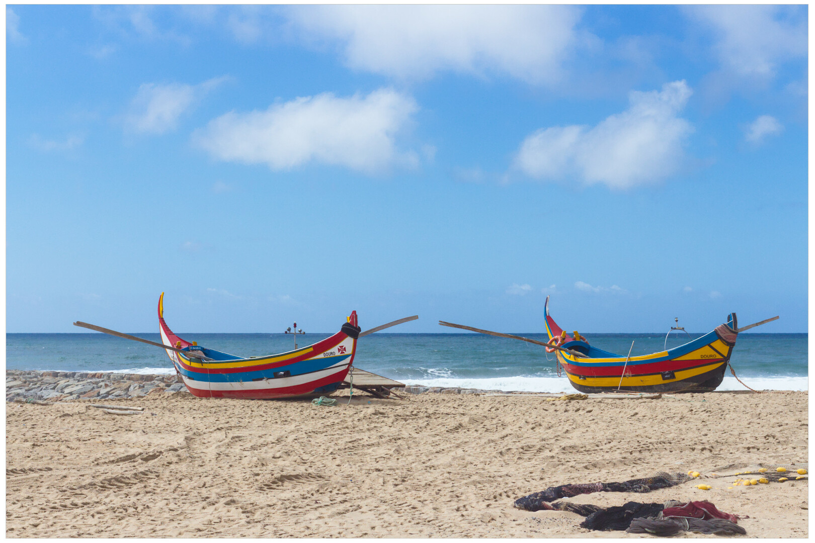 2 colourful boats on the beach on a blue day with a couple of clouds.

2 barcas de cores usadas na arte xábega na praia nun día azul cun par de nubes brancas. (galego).