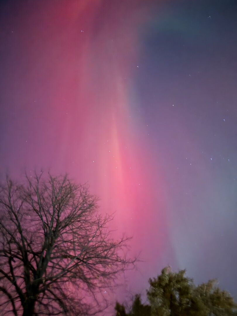Photo of a red and purple smear of northern lights above a residential street