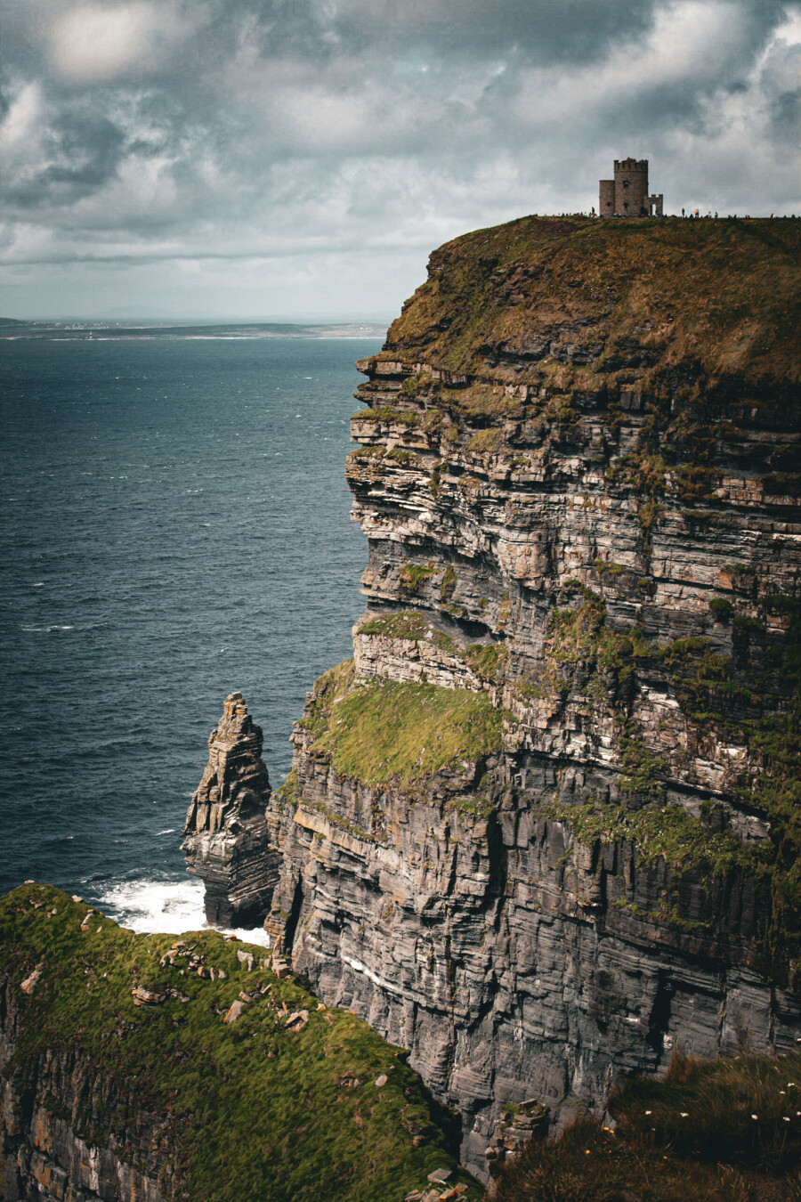 Cliffs with a small castle tower on top. The see to the left