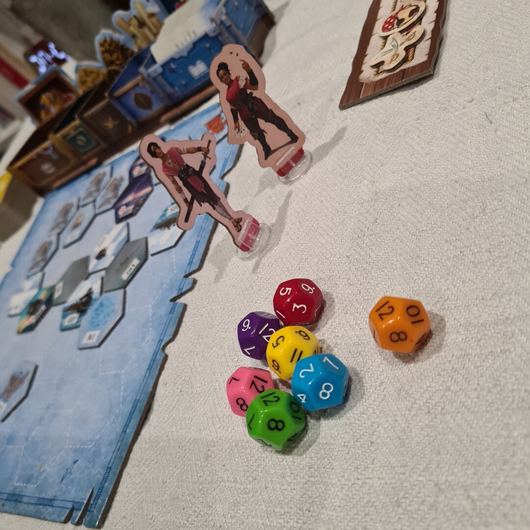 seven colourful d12 dice in the foreground. two pirate character board game tokens, and in the background a hex grid sea map.