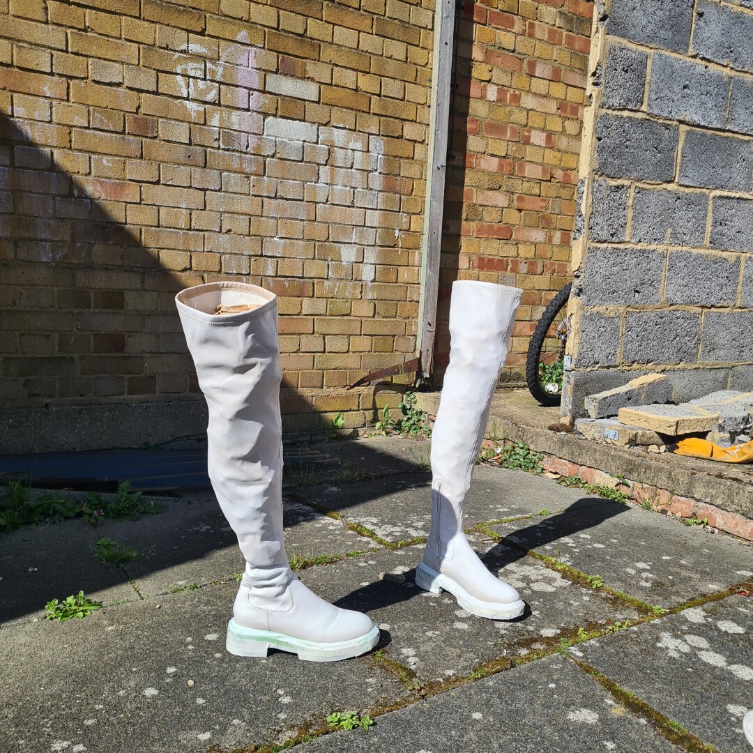 two long white boots standing in a yard, apparently able to stand by themselves