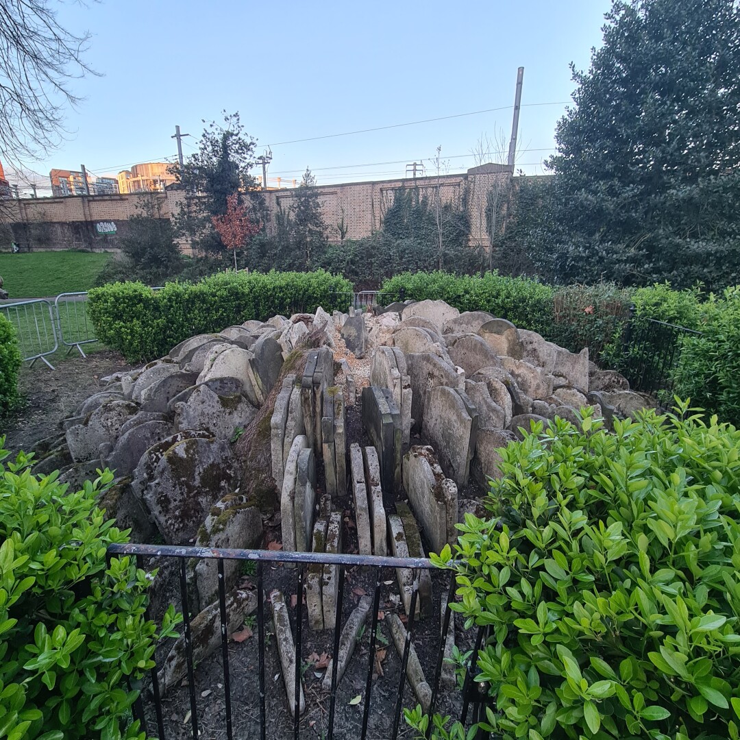 gravestones arranged in a circle, a fence and hedges surround the structure