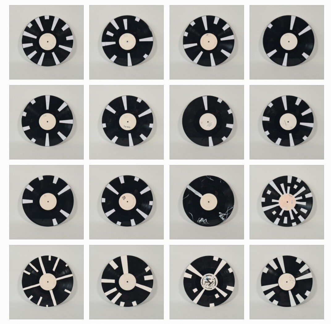 grid of sixteen vinyl records, each with white stickers on in various patterns.