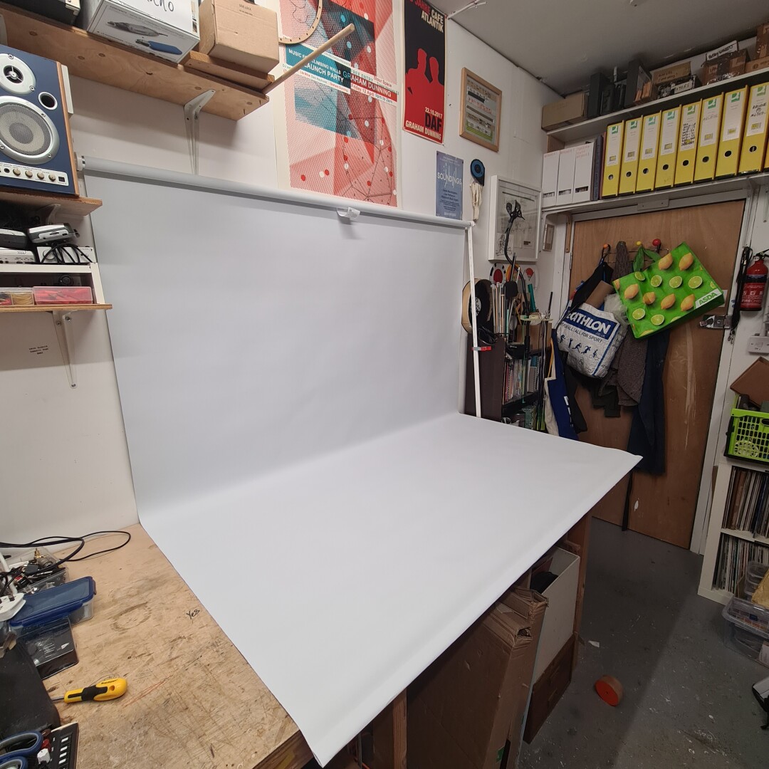 white roller blind attached to the wall and running over the desk.