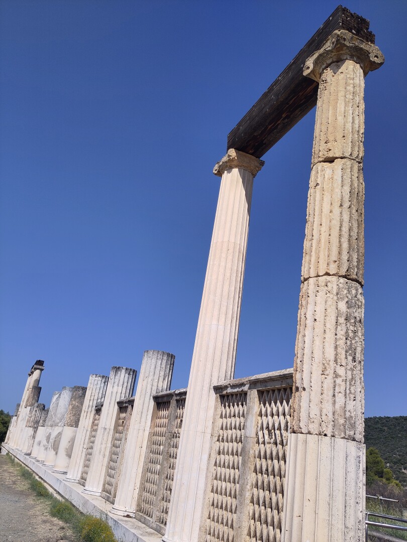 The bath of Asklepios, the remains consisting mainly of one wall of columns, the closest of which to the right were the tallest to stay intact - the rest of the columns are shorter, but also shrink into the distance towards the left. Apparently patients would stay at Epidaurus in hopes of healing: if they dream of Asklepios himself, they would. If only healthcare truly was that simple.