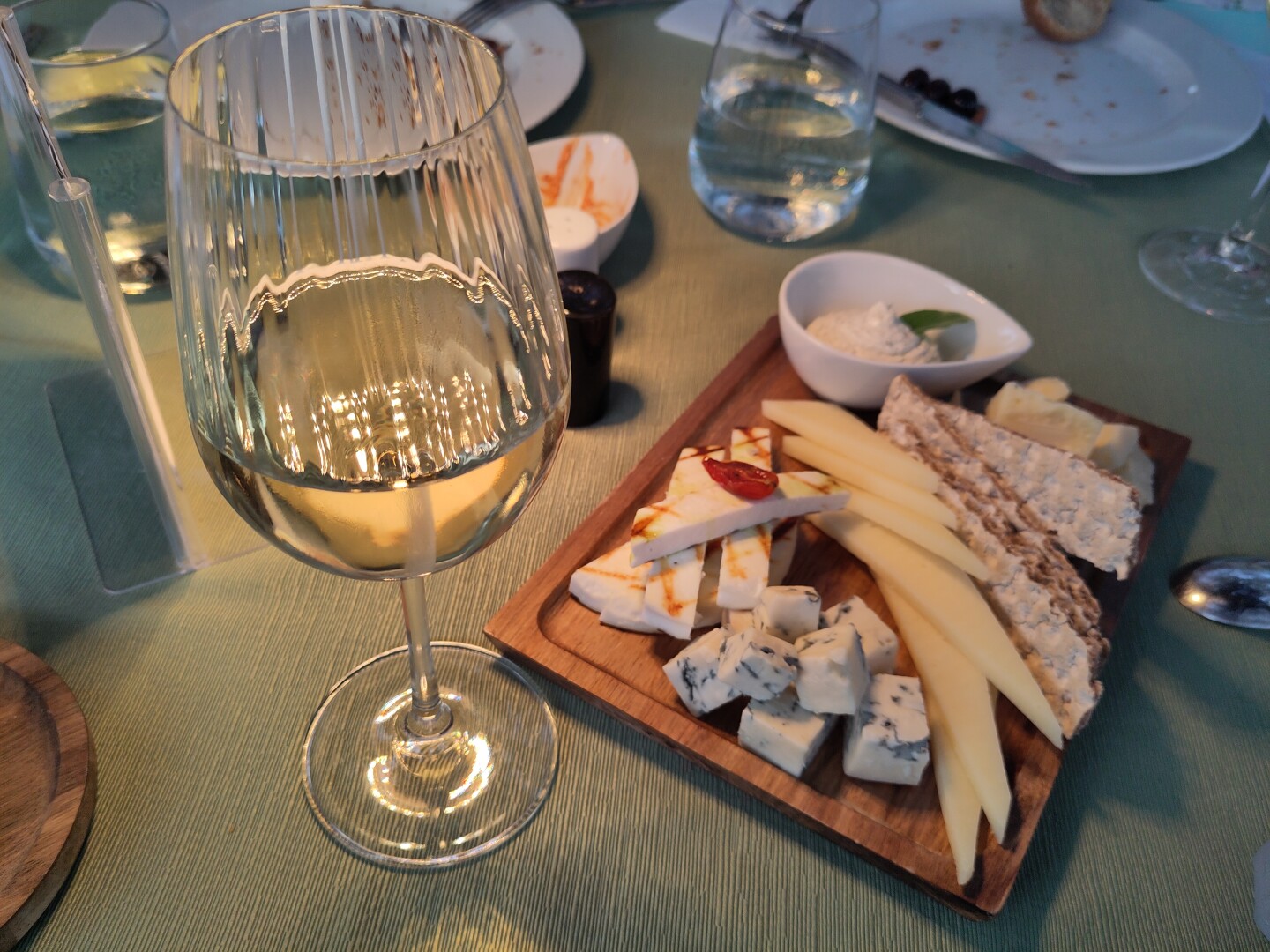 A glass of white wine sitting to the left of a plate decked out with different cheese slices. I can't remember the cheese names anymore, but they ranged from parmesan to blue cheese and were all delicious.