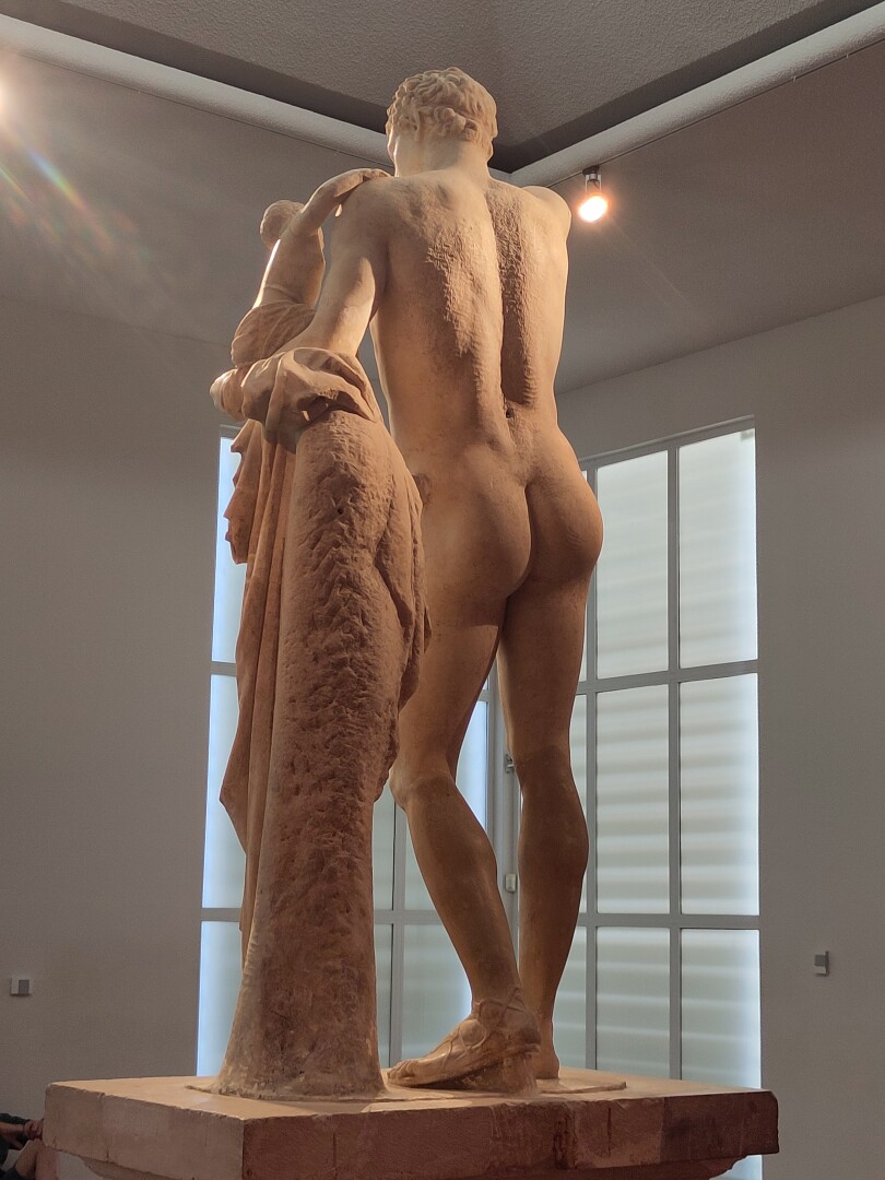 A tall statue of Hermes leaning on a low pillar, except taken from the back to show off his well-sculpted buttocks. Come on, look at them - I couldn't not!