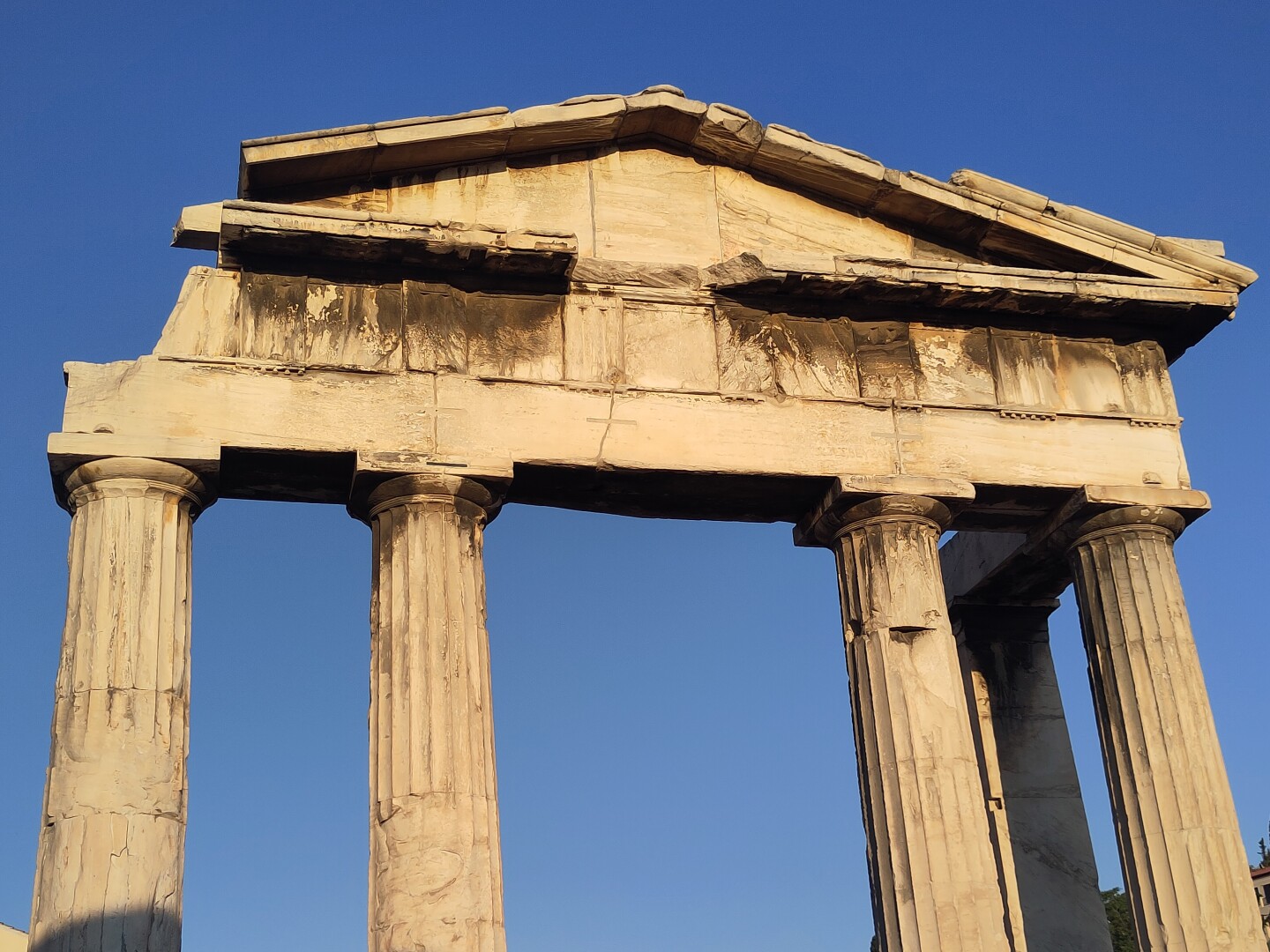 The temple facade of doric columns at the entrance of the Roman Agora in Athens against clear blue skies.