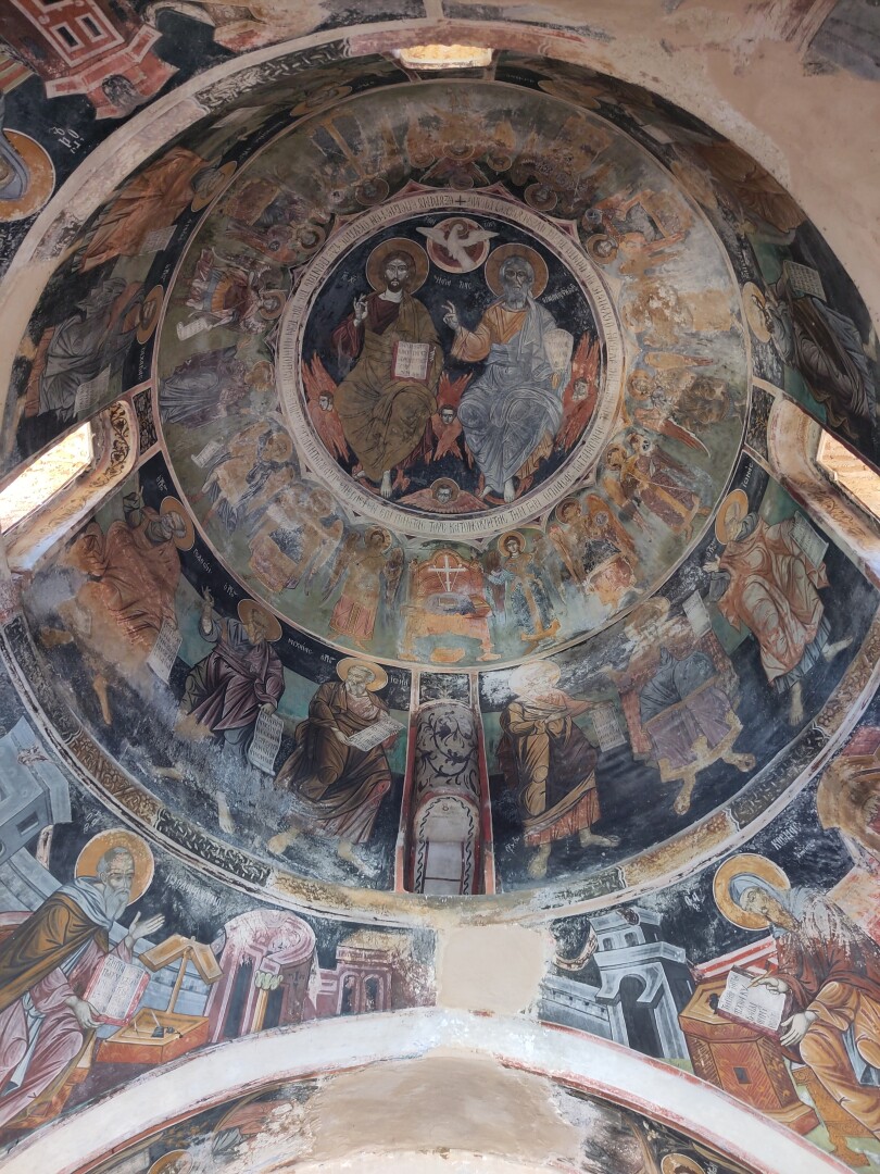 Inside shot of the byzantine church's dome, every inch decorated in beautiful frescoes of different saints surrounding a large Jesus and God in the center.