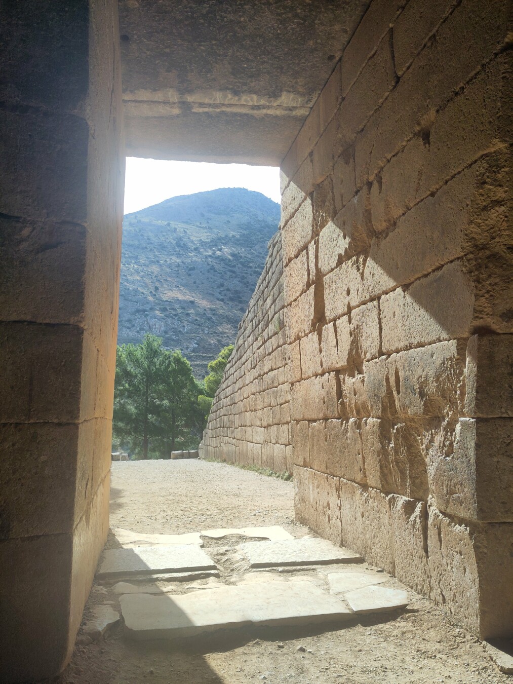 The view from just inside the Tomb to the green hilly landscape outside, framed within the entrance of more giant slabs of rock.